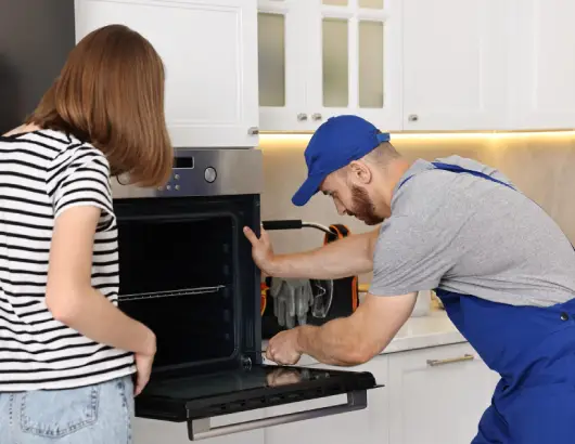 Appliance repair technician fixing oven in Burnaby.