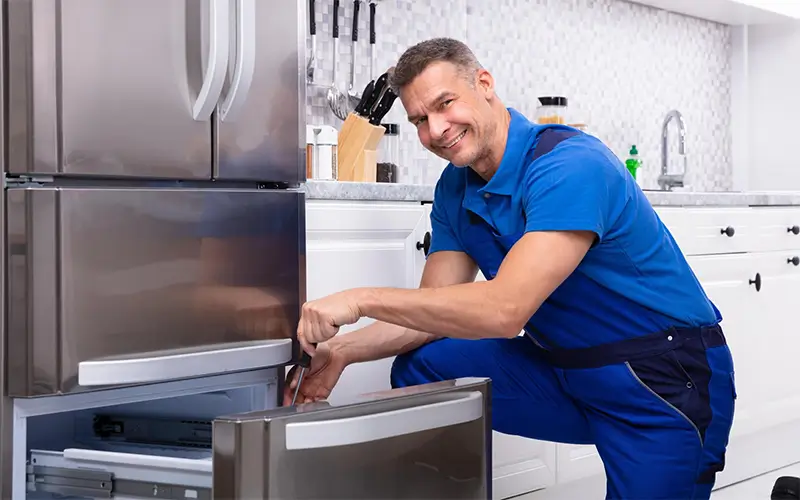 Friendly appliance repair technician fixing refrigerator drawer in modern kitchen