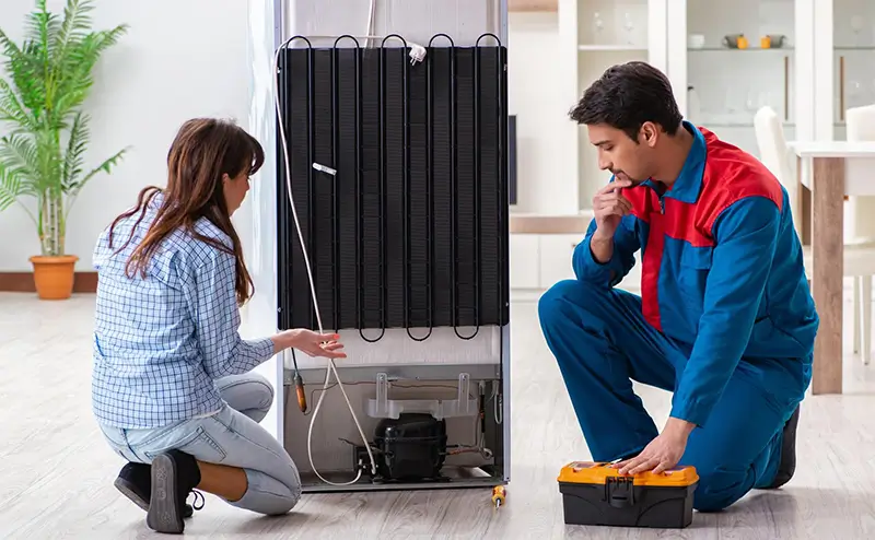 Appliance repair technician fixing fridge in Surrey.
